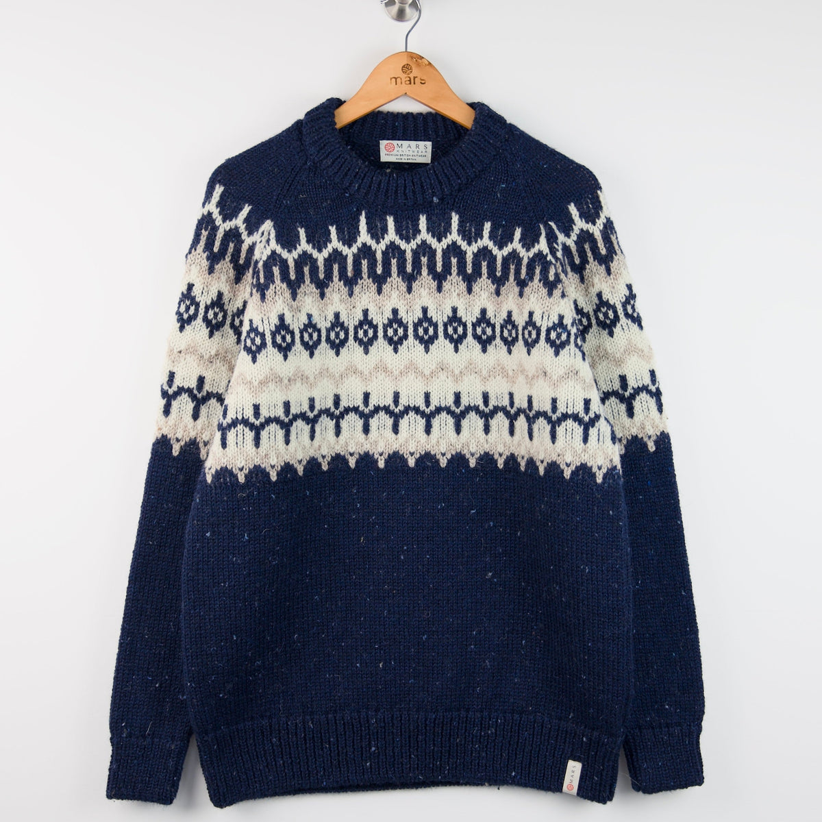 Navy blue and white patterned sweater on a wooden hanger against a white background